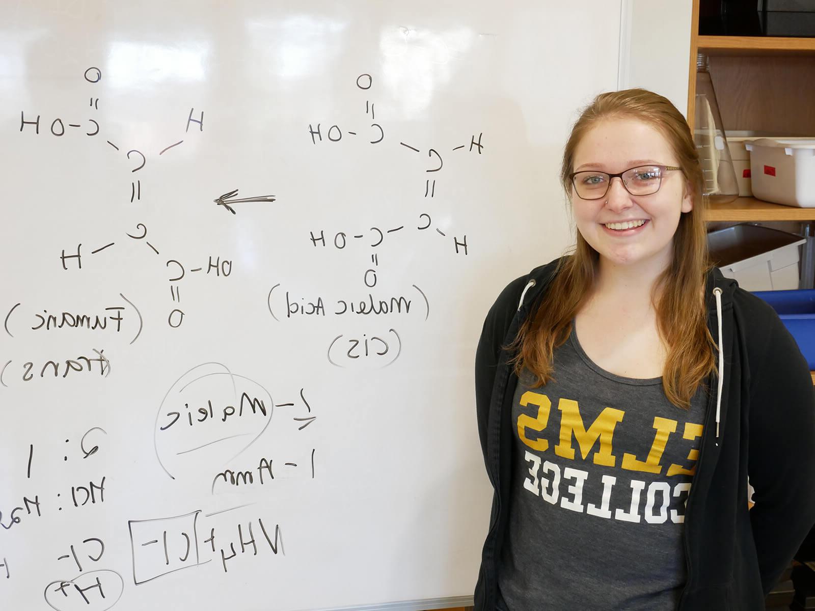 Photo of ElmSTEM scholar 和 chemistry major April Thresher in front of a white board.